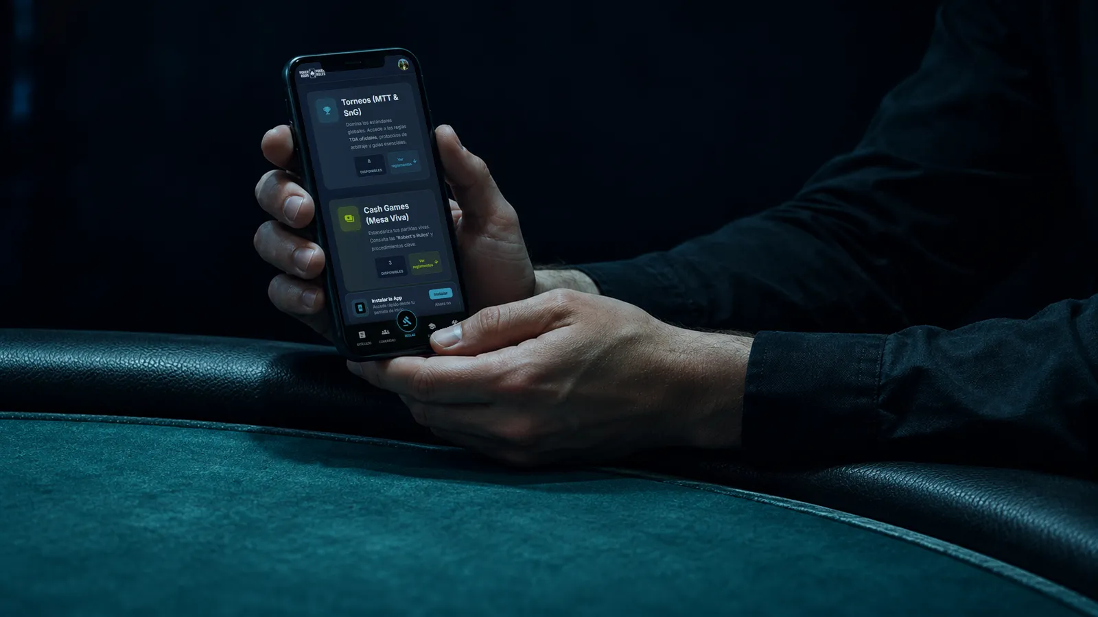Celular mostrando la app de PRPR con las secciones de Torneos y Cash Games, sostenido por las manos de un director junto a una mesa de póker